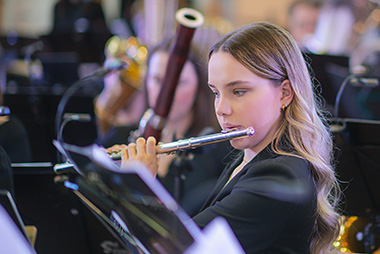 Junge Frau mit Querflöte im Orchester
